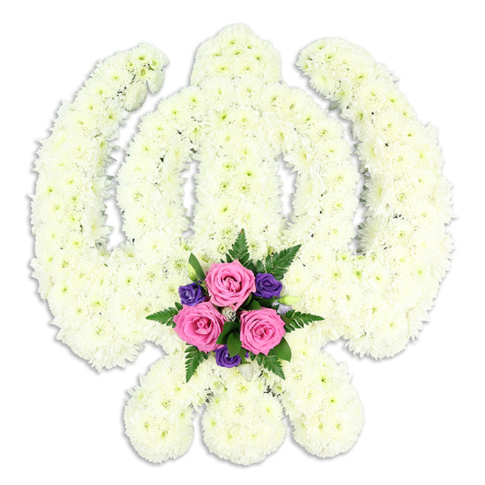 A stately Sikh Khanda floral design dominates the frame, its form captured in a sea of white chrysanthemums that glow softly against a minimalist white background. The double-edged sword stands upright at the centre, perfectly framed by the smooth, continuous circle of the Chakra, while the two curved Kirpans extend gracefully to either side, creating a balanced, symmetrical silhouette. Every contour of the symbol is carefully followed with flowers, so the outline appears crisp without losing its natural softness. The chrysanthemums themselves are small but full, their many petals overlapping to create a dense, velvety texture that suggests both purity and quiet strength. No stems or mechanics are visible; only the blooms form a continuous, pristine surface. At the lowest point of the arrangement, in the cradle formed by the crossed ends of the Kirpans, a cluster of coloured flowers draws the eye. Three blush-pink roses, fresh and full-headed, sit at the heart of this accent, their spiralled petals radiating gentle warmth. Around them, smaller deep purple flowers and fern-like greenery create a delicate frame, adding visual depth and a hint of garden softness to an otherwise formal tribute. Light from above falls evenly across the piece, producing only the faintest halo of shadow that hints at its depth. This kind of floral Khanda would often be chosen by Sikh families in Friern Barnet and nearby Bounds Green to accompany funeral rites, memorial services, or anniversaries of passing, offering a visible expression of faith, loyalty, and enduring love. It feels both traditional and personal, thoughtfully made to honour a cherished life with grace.