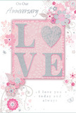 Resting as if just set down beside a vase of fresh flowers in a Friern Barnet home, this anniversary card radiates a sense of quiet, enduring romance. Its main feature is the word LOVE, centred and raised from the surface, the letters outlined with a fine dusting of glitter that glows in a palette of blush pinks, pearly whites, and shimmering silvers. The texture of the letters would feel slightly rough and pleasingly substantial, giving a tactile emphasis to the sentiment. Surrounding this central word, a series of delicate blooms unfurl across a pastel pink background. The flowers are illustrated with flowing, almost calligraphic lines, their petals soft and rounded, touched with hints of blush, mauve, and pale grey. Graceful vines and slender leaves twist gently between the blossoms, forming a loose, swirling frame that suggests the movement of a bouquet being turned in a florist's hands on Friern Barnet Road. Subtle silver detailing adds small points of sparkle, echoing the effect of light catching on glass or ribbon. The background shade of pink is soft and even, lending a sense of warmth and intimacy, as though the card is bathed in late-afternoon light. In elegant, understated script, phrases such as On Our Anniversary and I love you today and always are written with a careful rhythm, spaced so they complement rather than crowd the floral design. The card as a whole feels like a tender, paper version of a romantic arrangement - thoughtful, gently luxurious, and made to honour the shared journey of an anniversary couple in Friern Barnet.